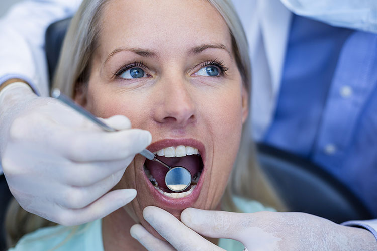 Clínica Dental Andrea Compte, tu Centro Odontológico especializado. Cirugía bucal en Cálig. Dentista examinando a la paciente.