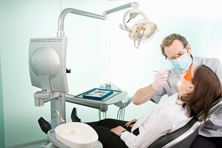 Clínica Dental Andrea Compte, tu Centro Odontológico especializado. Cirugía bucal en Santa Magdalena. Un dentista en cirugía que examina a un paciente.