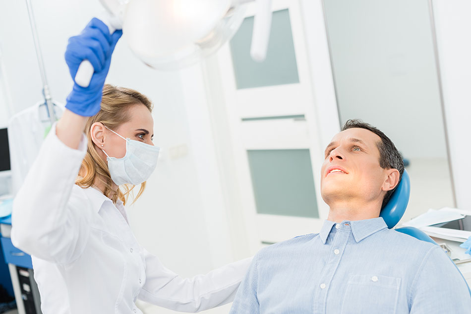 Clínica Dental Andrea Compte, tu Centro Odontológico especializado. Enfermedad periodontal en Sant Jordi. Dentista alumbrando con la lámpara al paciente.