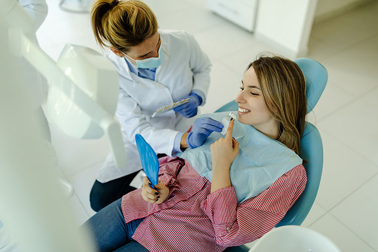 Clínica Dental Andrea Compte, tu Centro Odontológico especializado. Implantes dentales (Implantología) en Benicarló. Mujer seleccionando el mejor color de los implantes usando muestras de dientes.
