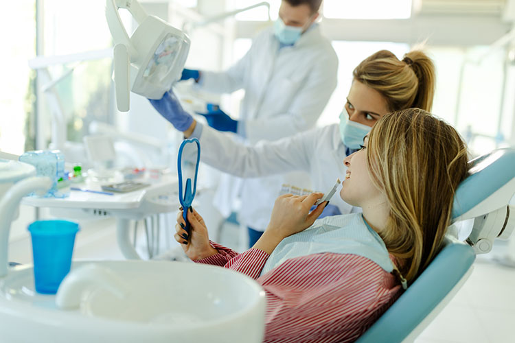 Clínica Dental Andrea Compte, tu Centro Odontológico especializado. Implantes dentales (Implantología) en Cervera del Maestre. Mujer escogiendo el color de los implantes usando muestras de dientes.