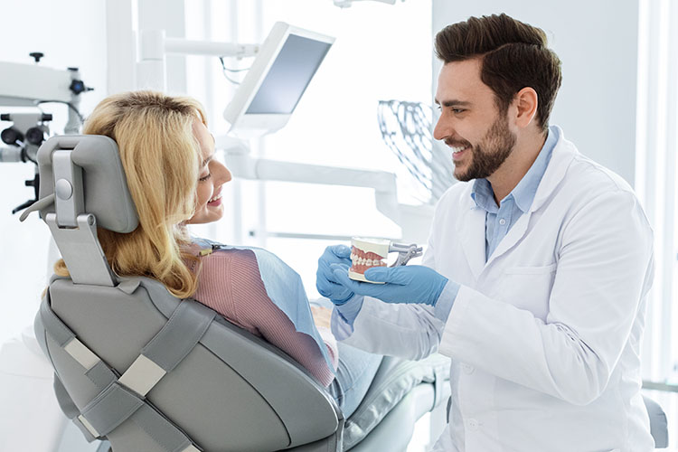 Clínica Dental Andrea Compte, tu Centro Odontológico especializado. Odontología en Cervera del Maestre. Dentista mostrando una mandíbula artificial a paciente.
