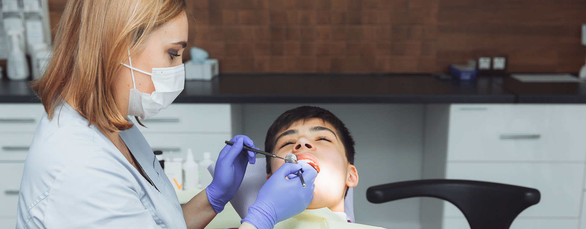 Clínica Dental Andrea Compte, tu Centro Odontológico especializado. Odontopediatría en Cálig. Odontóloga examina los dientes de un niño en la clínica.