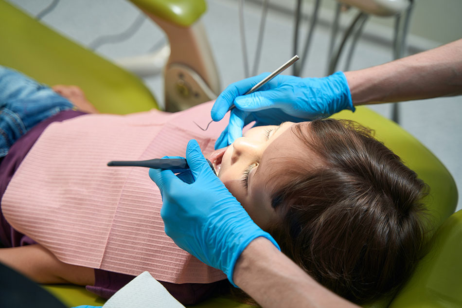 Clínica Dental Andrea Compte, tu Centro Odontológico especializado. Odontopediatría en Peñíscola. Dentista pediátrico inspeccionando la cavidad bucal de una niña.