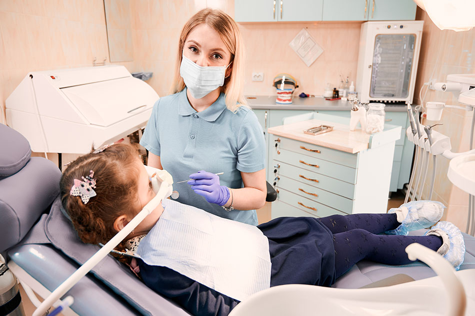 Clínica Dental Andrea Compte, tu Centro Odontológico especializado. Odontopediatría en Santa Magdalena. Dentista pediátrico que examina los dientes de la niña en el consultorio dental.