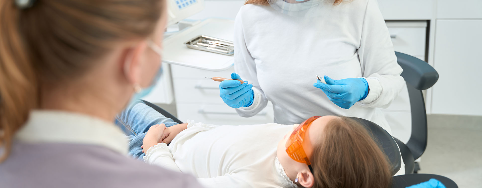 Clínica Dental Andrea Compte, tu Centro Odontológico especializado. Odontopediatría en Vinaròs. Dentista pediátrico que se prepara para examinar a la paciente.